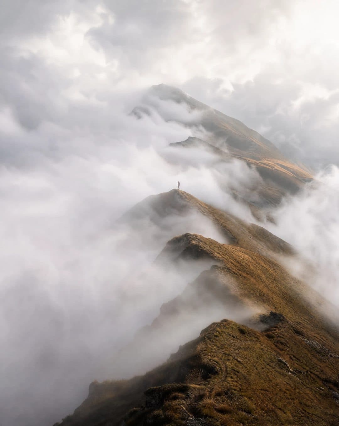 A lone figure on a mist-covered mountain ridge